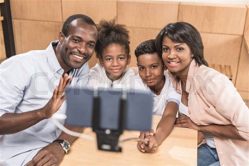 Happy african-american family taking selfie in cafe, stock photo