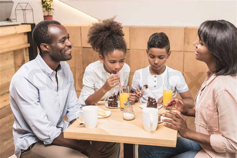 Adorable african-american family eating desserts in cafe, stock photo