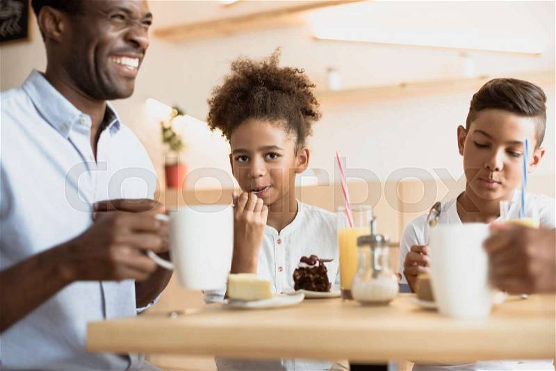 Adorable african-american father and kids in cafe, stock photo