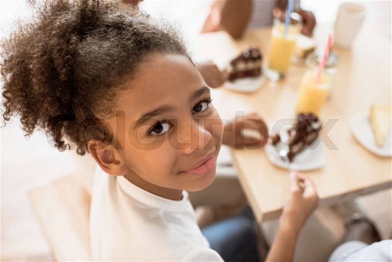 Happy african-american girl in cafe with desserts and juice, stock photo