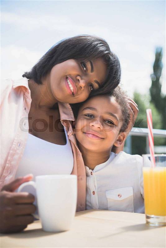 Happy african-american mother and daughter in cafe outdoors, stock photo