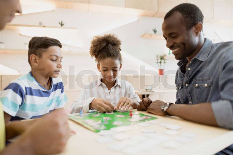 African-american family playing board game in cafe, stock photo
