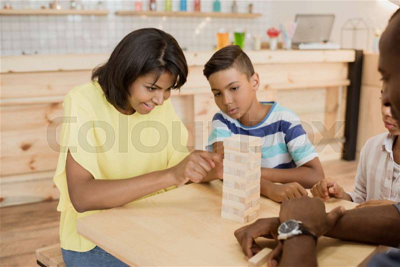 African-american family playing tower game in cafe, stock photo