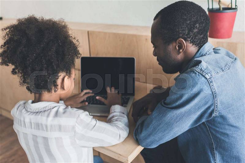 Pensive african-american father and daughter sitting in cafe with laptop, stock photo