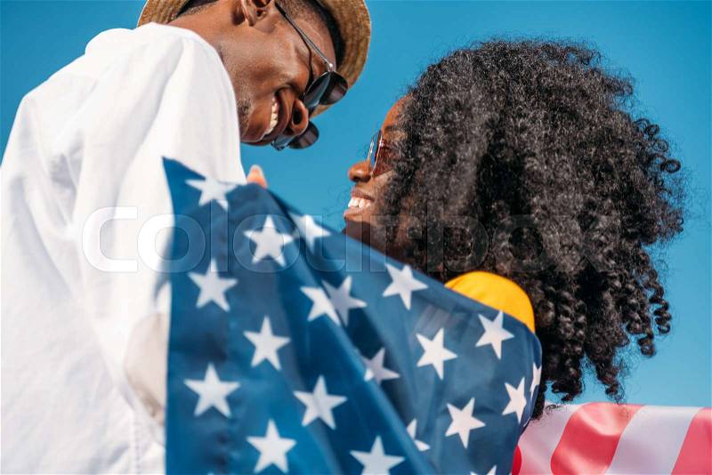 Young happy african american couple with america flag hugging each other, stock photo