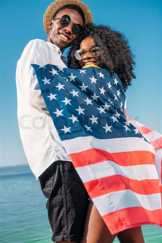 Young happy african american couple with america flag hugging each other, stock photo