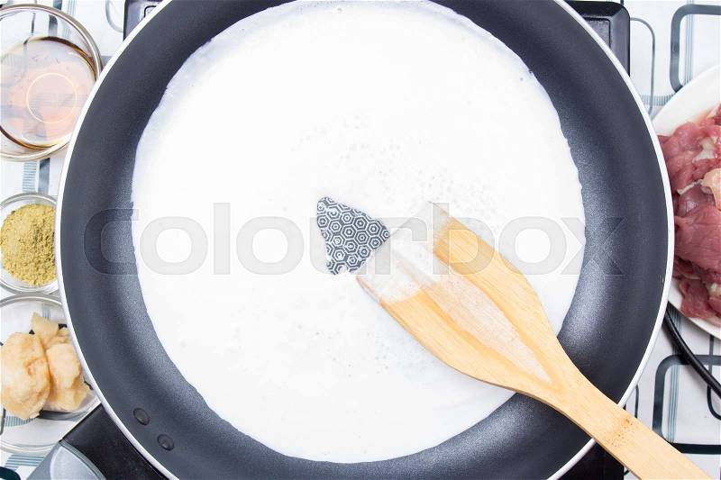Chef cooking coconut milk with turner / Cooking green curry concept, stock photo