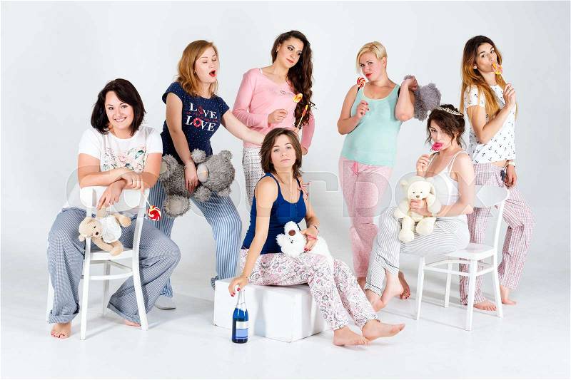 Girls in pajamas posing in studio. Happy female friends making pajama party. Women day, celebration, friends, bachelorette party, friendship, birthday and holidays concept, stock photo