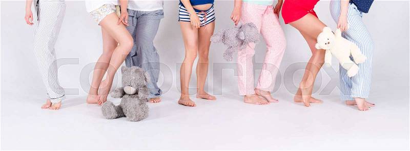 Girls in pajamas posing in studio. Female friends making pajama party. Women day, celebration, friends, bachelorette party, friendship, birthday and holidays concept. Unrecognizable women, only legs, stock photo