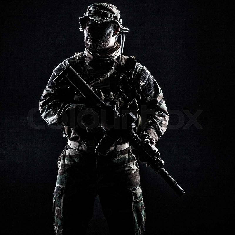 Bearded Special forces United States in Camouflage Uniforms studio shot half length. Holding weapons, wearing jungle hat, Shemagh scarf, he is ready to kill. Contour shot, backlit, stock photo