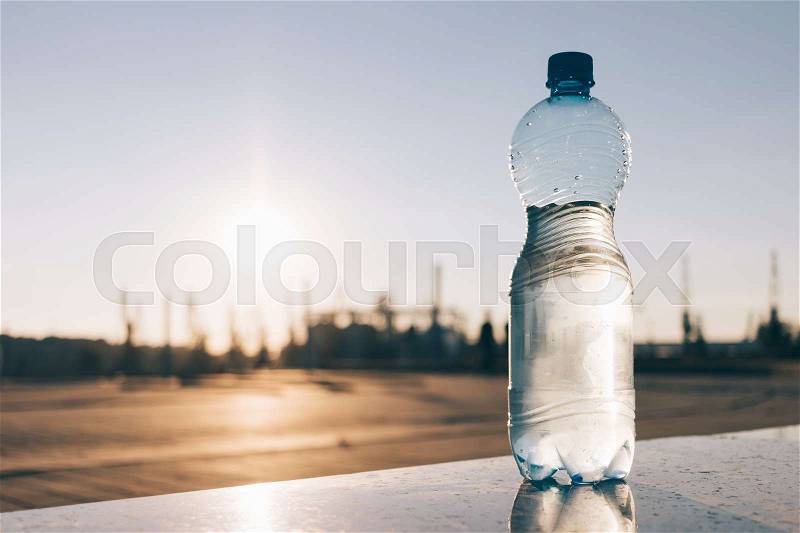 Plastic bottle of cold mineral water outdoors, stock photo