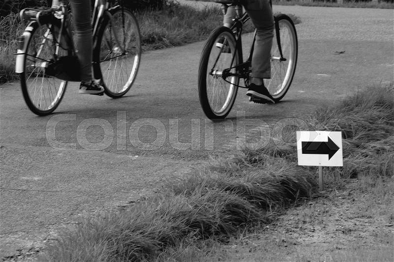 Couple, man and wife are biking along the marked route for the runners in the park at the country side in the summer in black and white, stock photo
