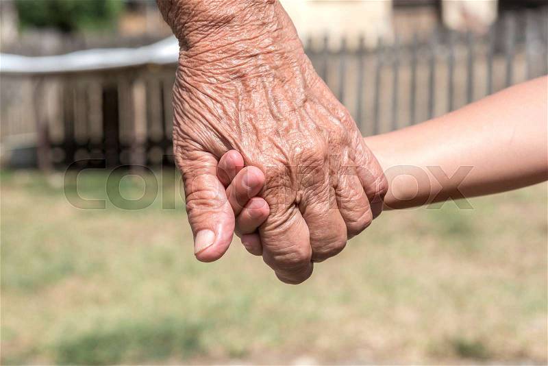 Old female holding young kid for her hand, stock photo