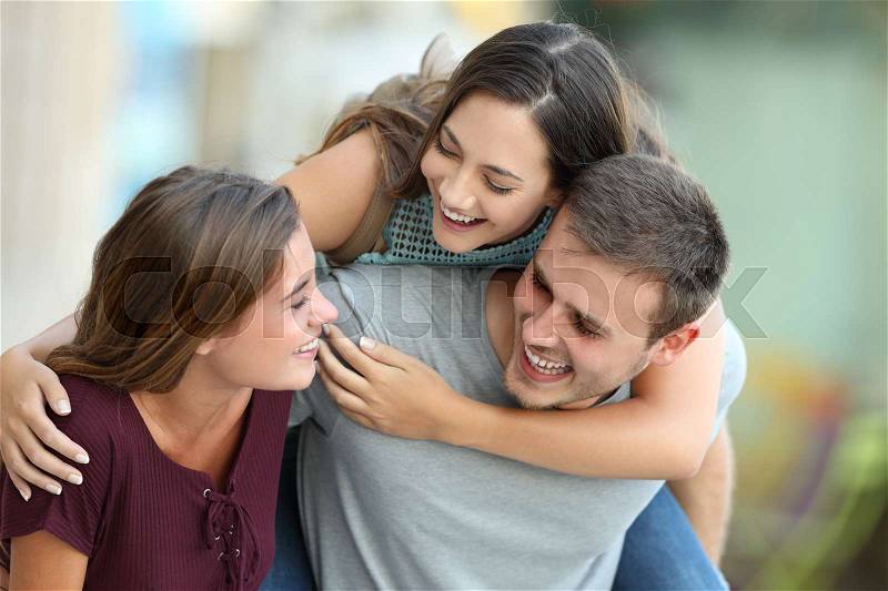 Three happy friends meeting and joking together on the street, stock photo