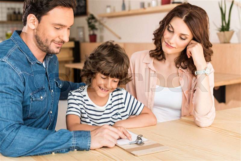 Beautiful young family in cafe looking at paycheck, stock photo