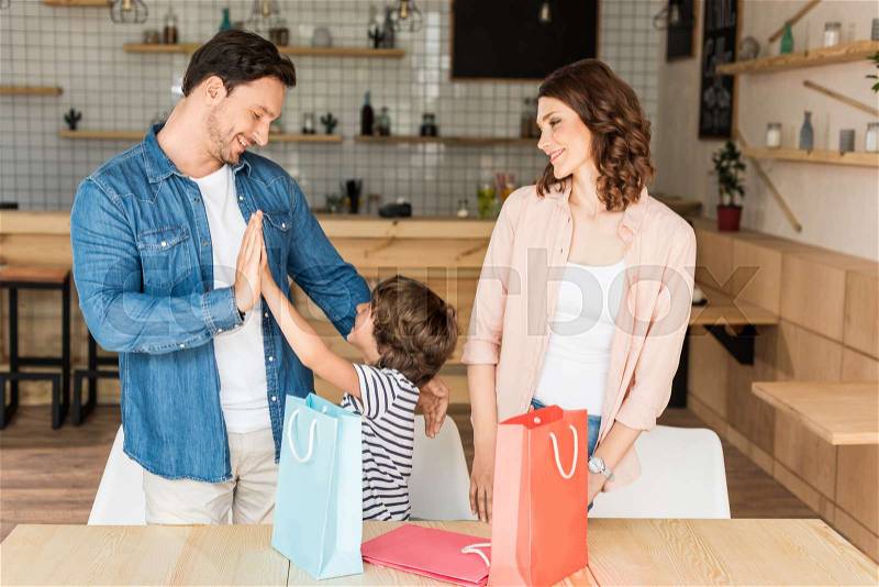 Beautiful young family with shopping bags in cafe, stock photo