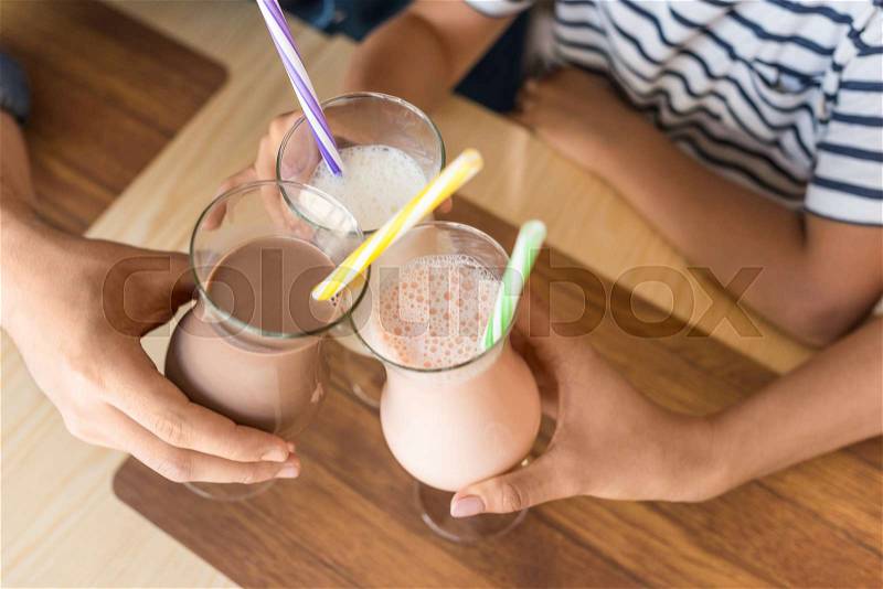 Cropped shot of family clinking with glasses of milkshakes, stock photo