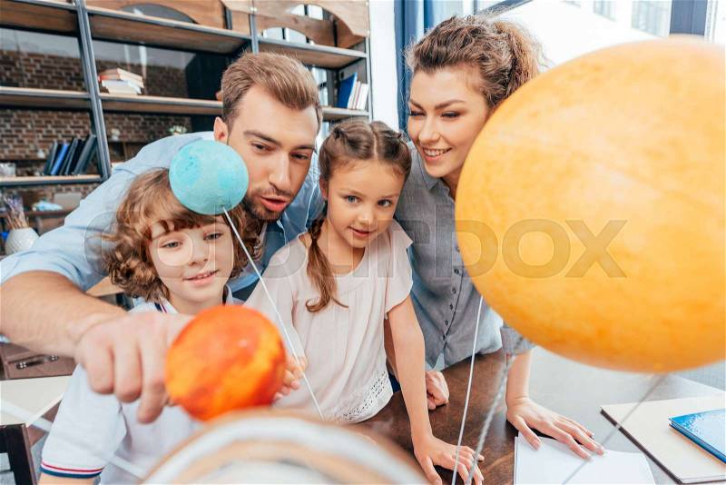 Adorable family making solar system model for school project, stock photo