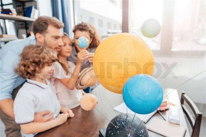 Young happy family making solar system model for school project, stock photo