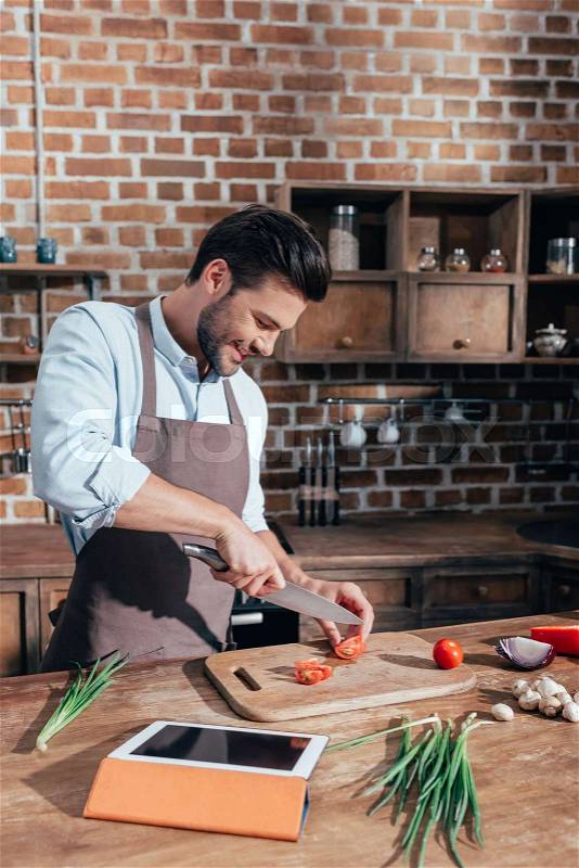 Happy young man cooking with tablet, stock photo