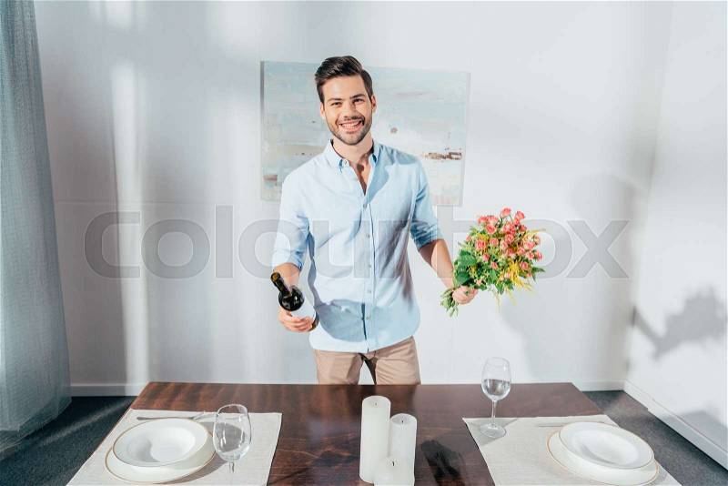 Handsome young man with bouquet of flowers and wine, stock photo