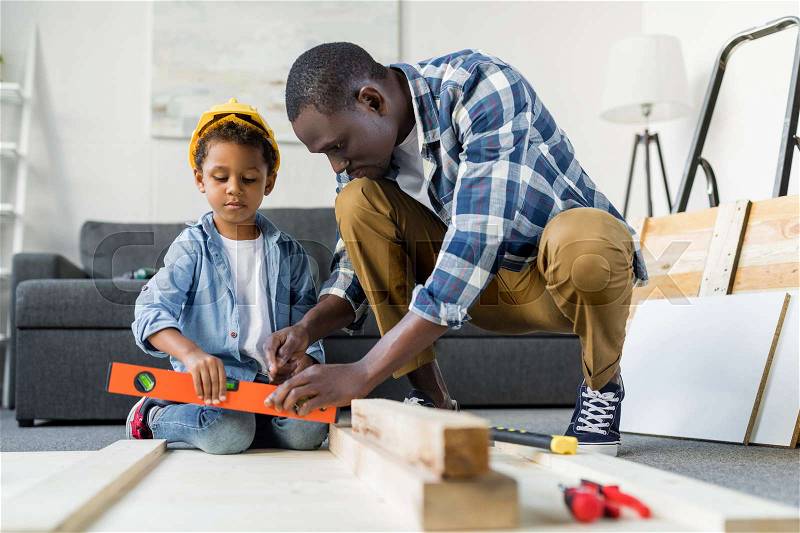 African-american father teaching his son how to use tools, stock photo