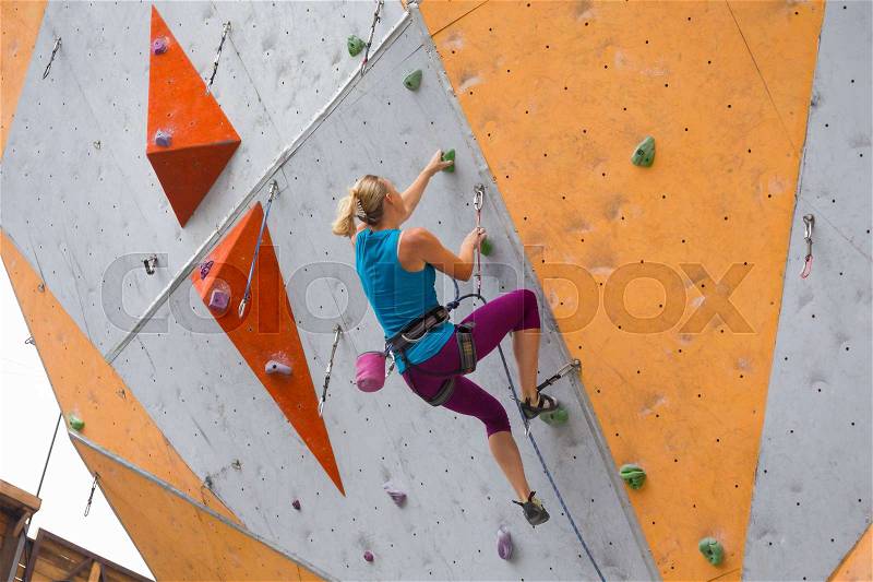 Bouldering, girl climbing up the wall , stock photo