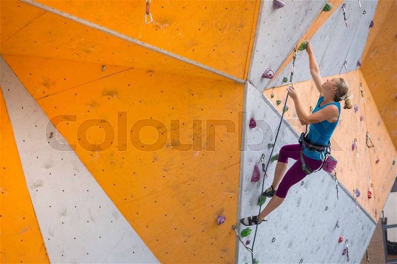 Bouldering, girl climbing up the wall , stock photo