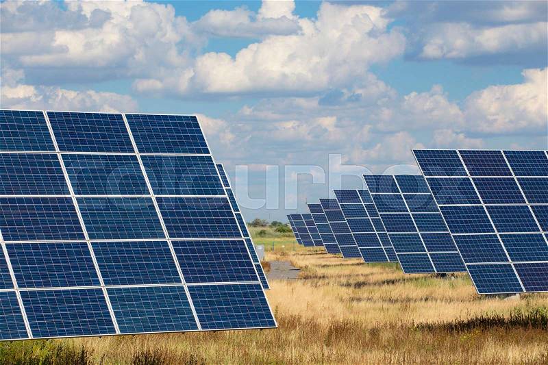 Solar panels standing at the field at the bright sunny day , stock photo