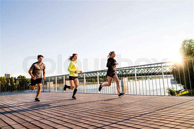 Beautiful young athletes in the city running at the river, stock photo