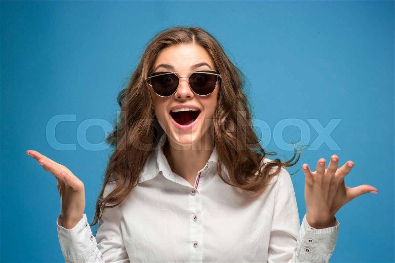 The young woman\'s portrait with happy emotions on blue background, stock photo