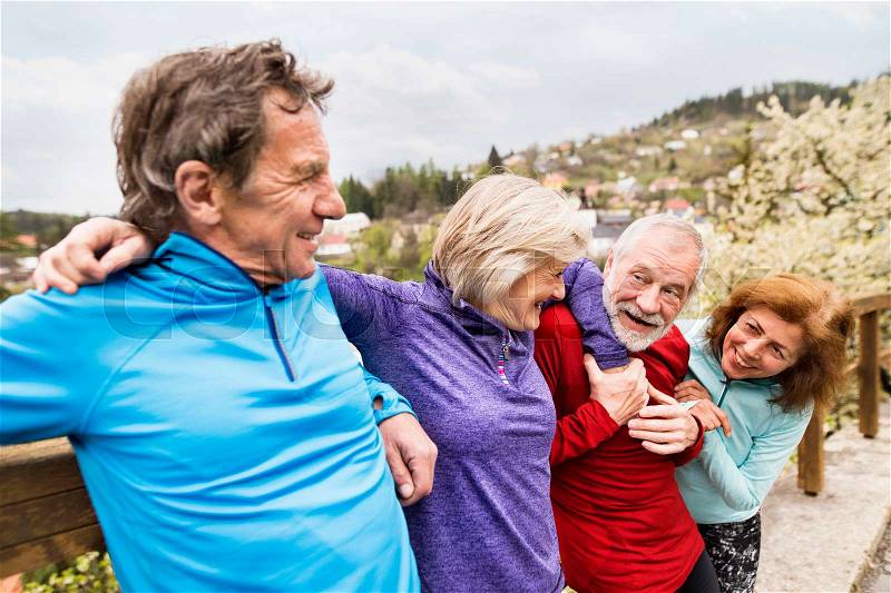 Group of active senior runners posing together outdoors in the old town of Banska Stiavnica in Slovakia, stock photo