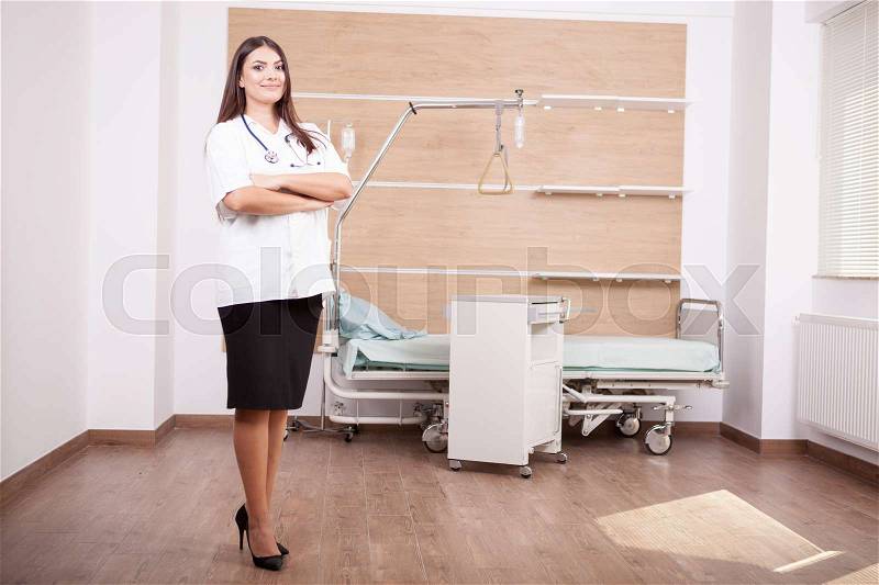 Smiling brunette woman doctor on hospital background. Medicine and healthcare, stock photo