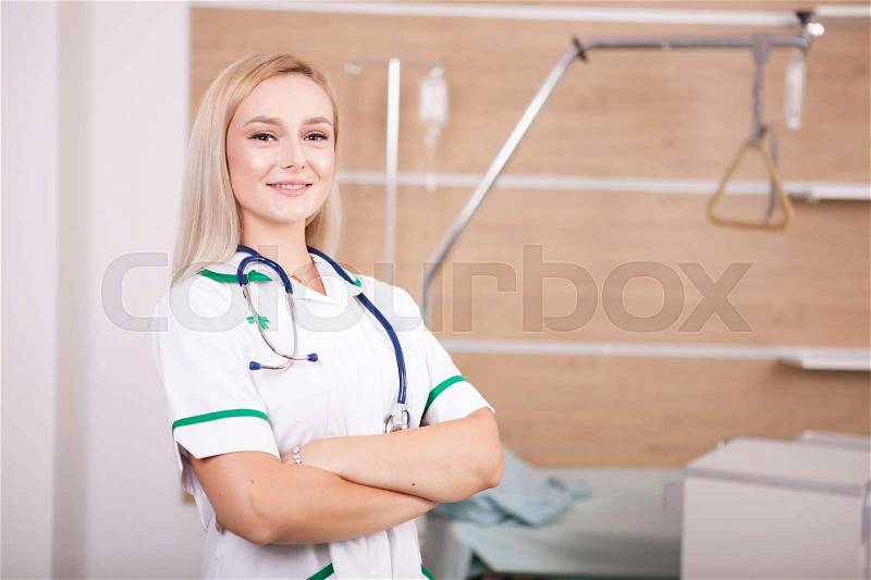 Smiling blonde woman doctor on hospital background. Medicine and healthcare, stock photo