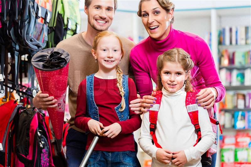 Family with two kids choosing school satchel in store, mother, father and children looking into the camera, stock photo
