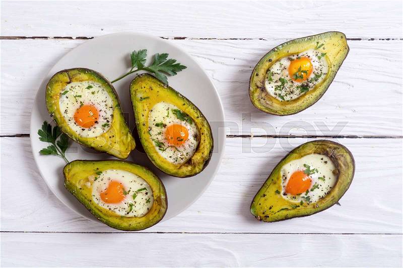 Baked avocado with eggs on woode background , top view , stock photo