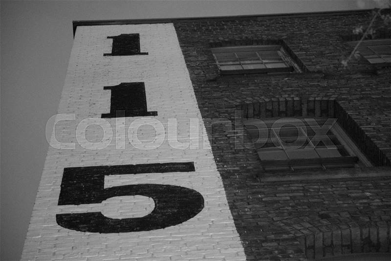 Big numbers one five on bricks building facade windows evening, stock photo