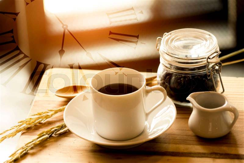 Double exposure of coffee time with vintage watch, hot cup and bottle of coffee seed and honey syrup on wooden table in the morning , stock photo