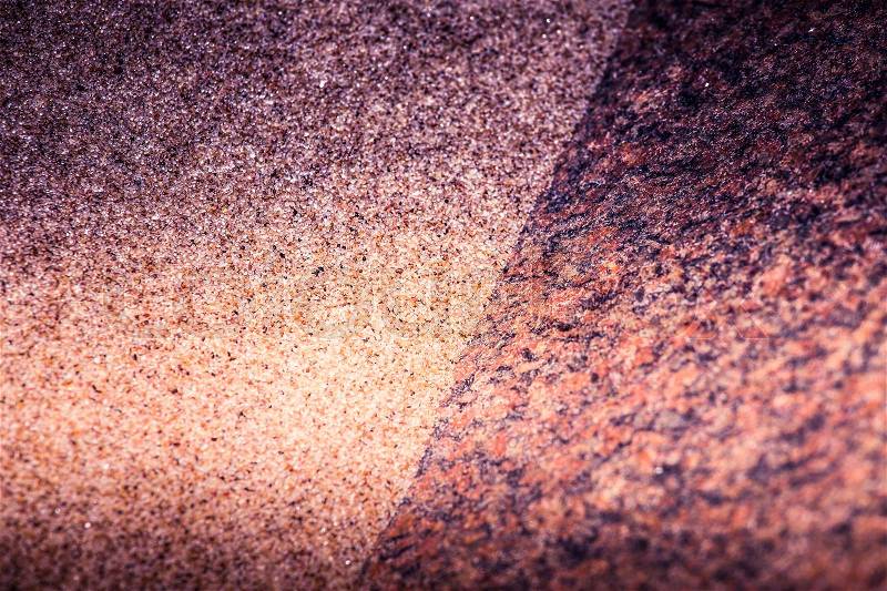 An abstract, high contrast background of a sea sand and rock shapes. Shallow depth of field, purple color tone, stock photo
