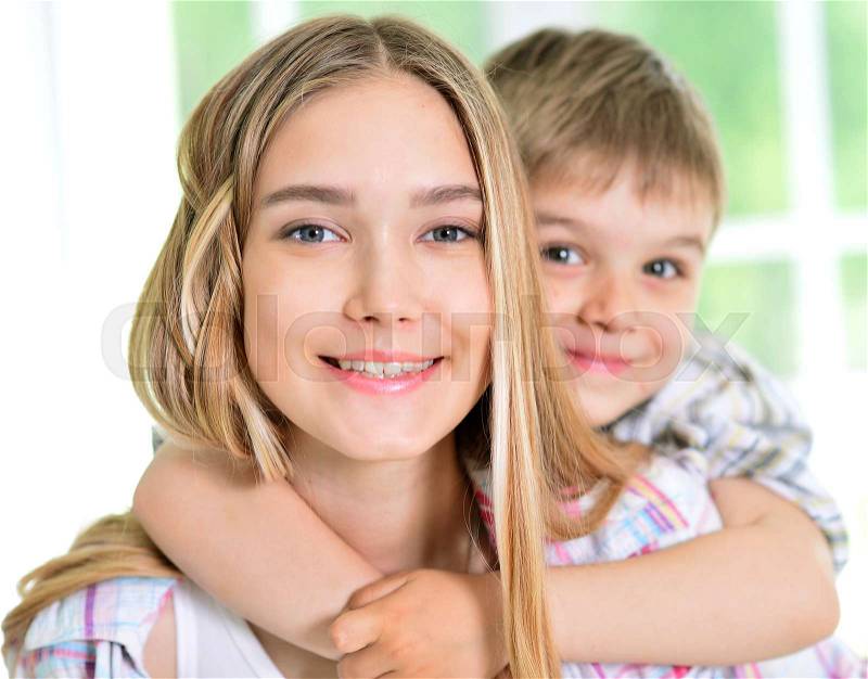 Close up portrait of little brother hugging his sister, stock photo