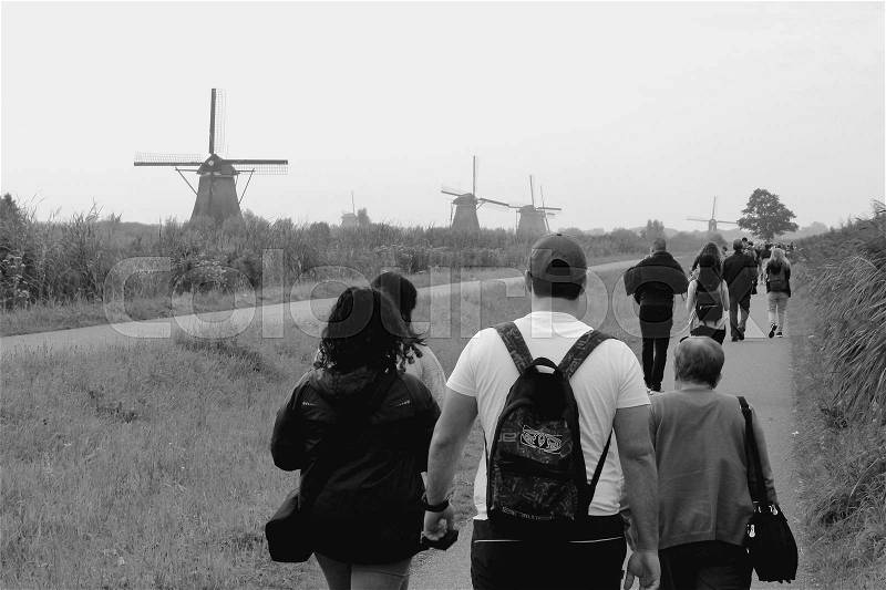 The tourists are walking to the windmills at Kinderdijk in Holland in the summer in black and white, stock photo
