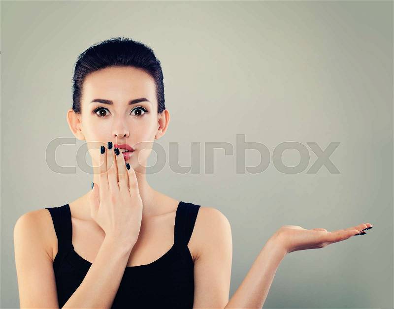 Happy Surprised Woman Woman Showing Empty Open Hand. Young Model with Empty Hand and Fashion Makeup on Banner Background, stock photo