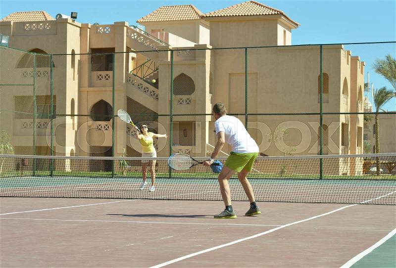 Husband and wife playing tennis at court, stock photo