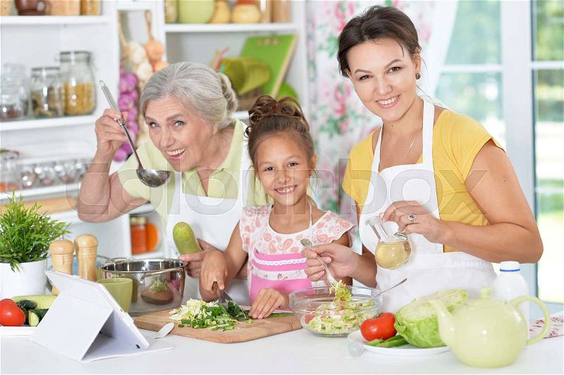 Three female generations of one family preparing dinner at kitchen, stock photo