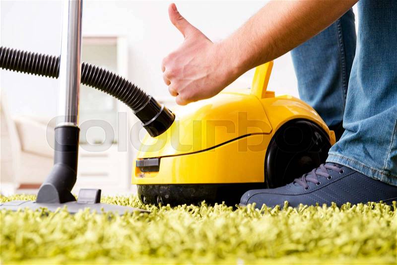 Man cleaning the floor carpet with a vacuum cleaner close up, stock photo