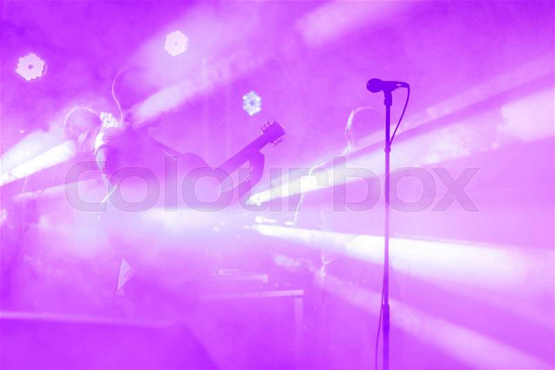 Guitarist silhouette perform on a concert stage. Abstract musical background. Music band with guitar player. Playing guitar and concert concept. Live music, festival background. Instrument on stage, stock photo