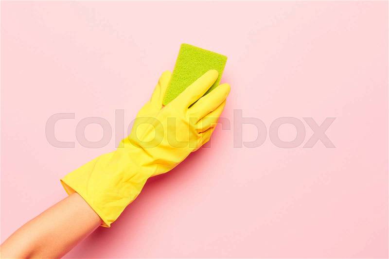The woman\'s hand cleaning on a pink background. Cleaning or housekeeping concept background. Frame for text or advertising, stock photo