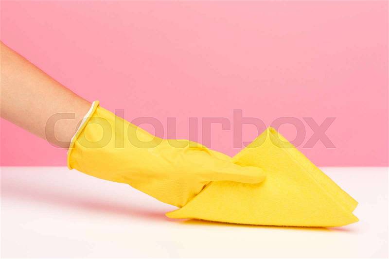 The woman\'s hand cleaning on a pink background. Cleaning or housekeeping concept background. Frame for text or advertising, stock photo
