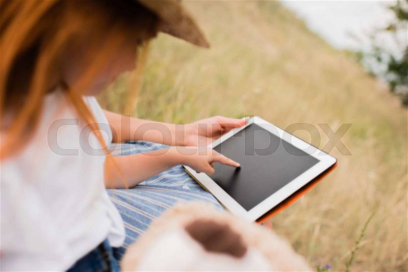 Cropped shot of mother and daughter using digital tablet with blank screen outdoors, stock photo