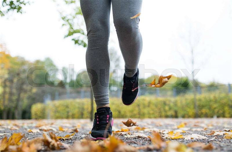Fitness, sport, people, wear and healthy lifestyle concept - close up of young woman running in autumn park, stock photo